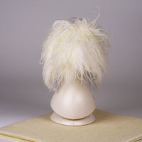 A white synthetic fiber dog wig displayed on a mannequin head, resembling a fluffy dog with black eyes and a pink collar.