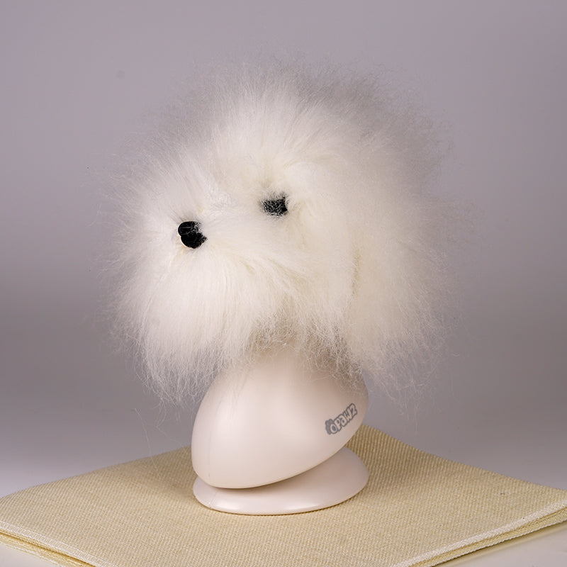 A white synthetic fiber dog wig displayed on a mannequin head, resembling a fluffy dog with black eyes and a pink collar.