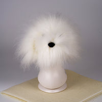 A white synthetic fiber dog wig displayed on a mannequin head, resembling a fluffy dog with black eyes and a pink collar.