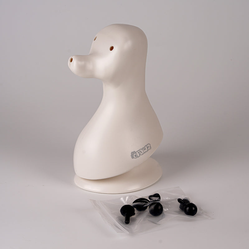 A plastic model of a dog head, designed in a teddybear style with black eyes, on a plain background.